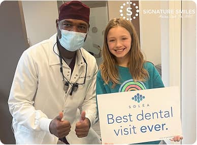 Signature Smiles | Dentist and young patient smiling holding best dental visit ever sign